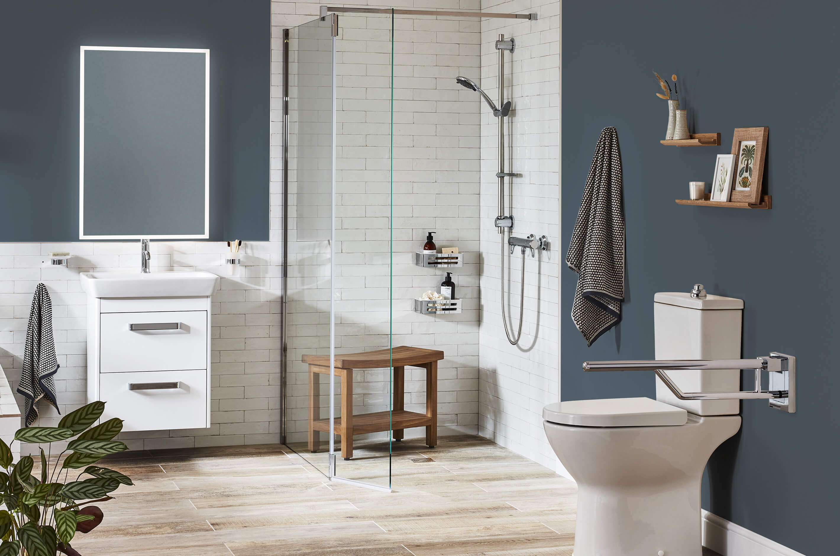 Fine & Able accessible wetroom with white metro tiles and blue walls, wooden shower bench in shower enclosure, grabrails, comfort height toilet.