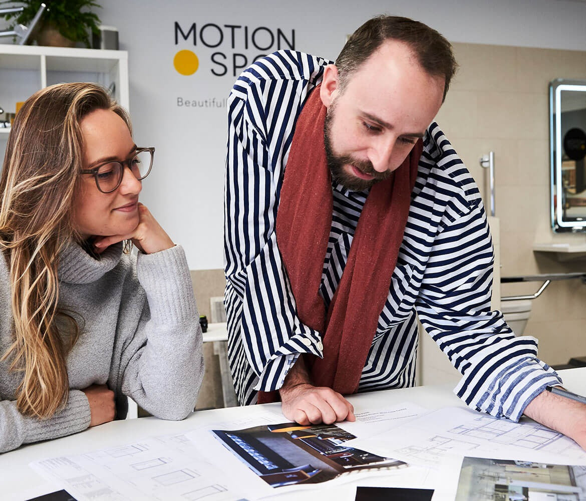 Two people looking at and discussing designs on the table in front of them.