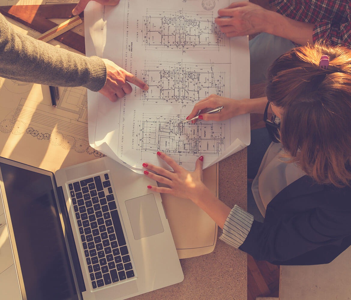 Designers sitting around a table using blueprints to plan.