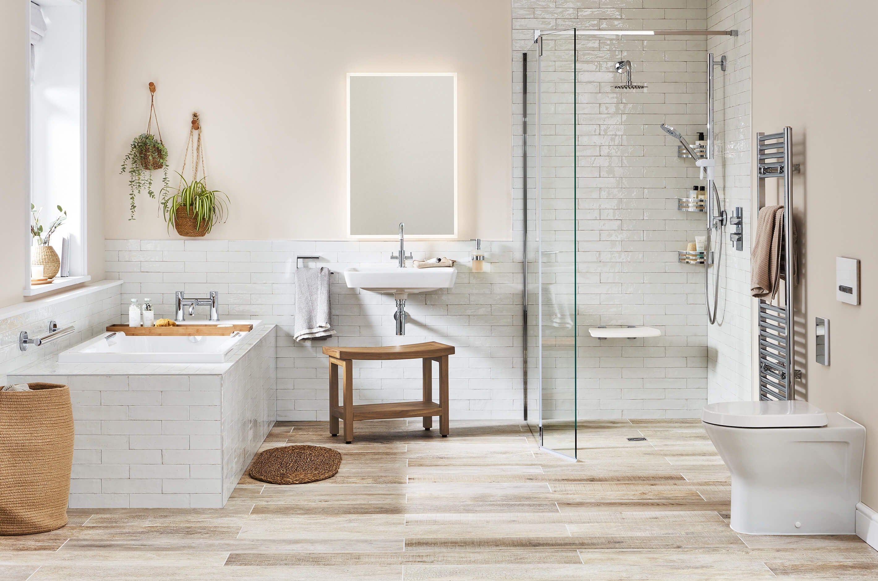 Neutral toned Fine & Able accessible bathroom with level access shower enclosure, wall mounted shower seat, and basin with wooden bench below.