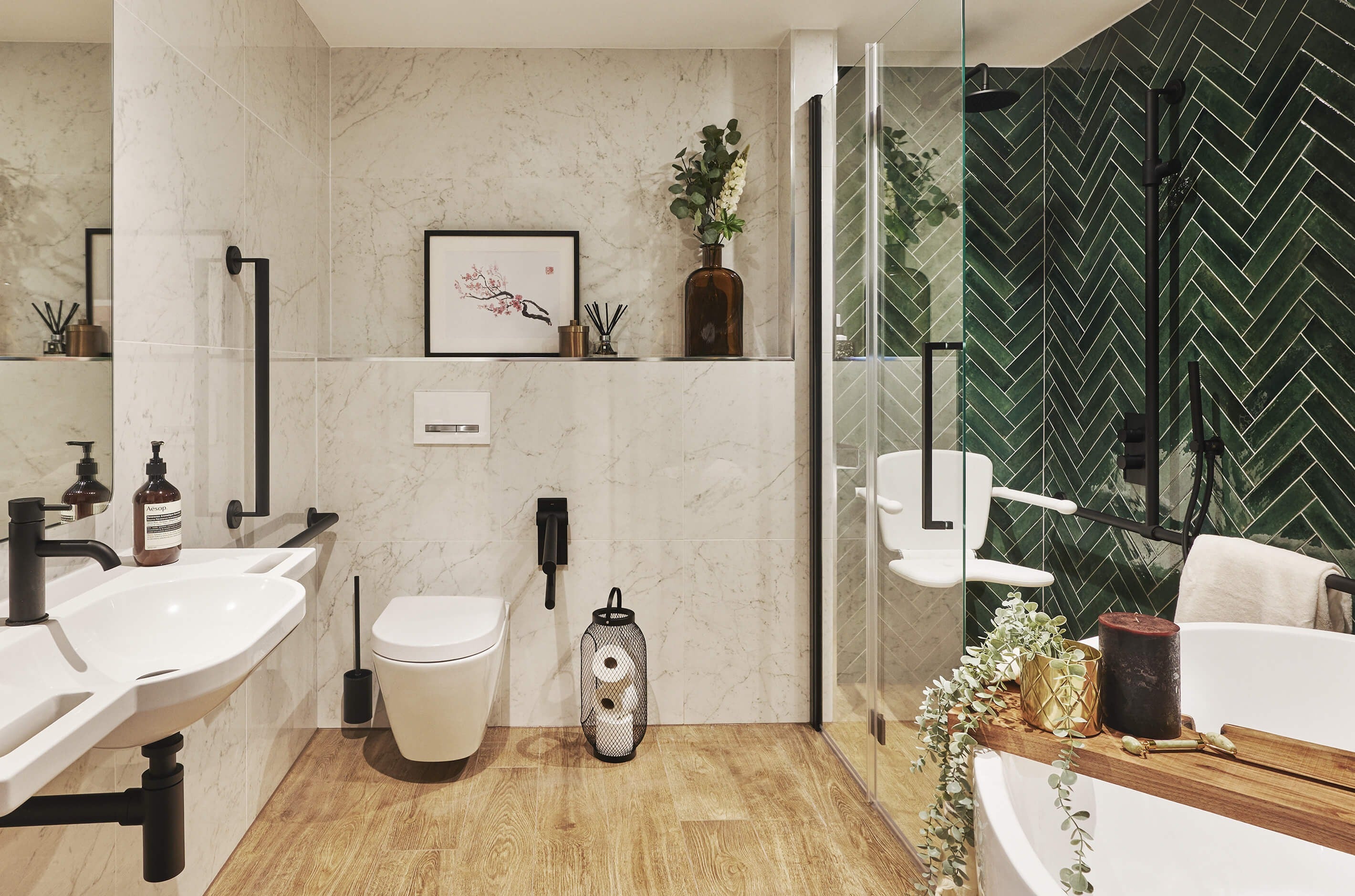 Fine & Able accessible bathroom with white marble and rich green tiles, matt black grab rails and wood effect floor tiles.