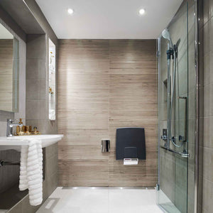 natural toned shower area featuring Modum shower seat and chrome grab rail